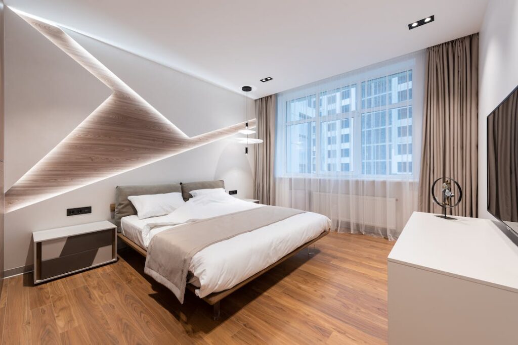 A modern bedroom with a large bed and beige decor.