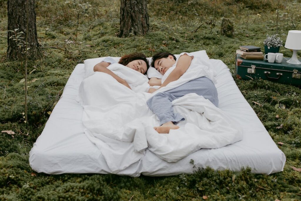 A couple lying on the mattress outdoors.