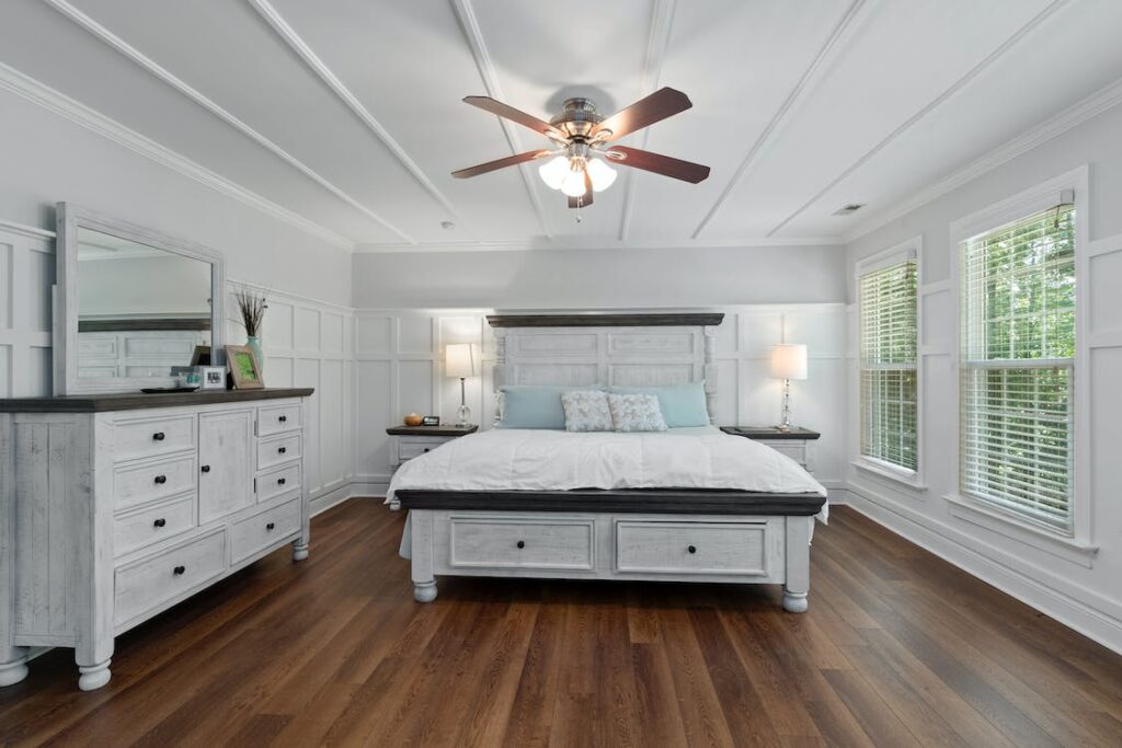 A contemporary bedroom design with a wooden floor and white walls.