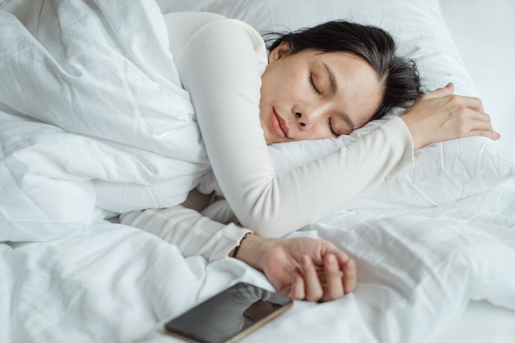 A woman lying in bed next to her phone