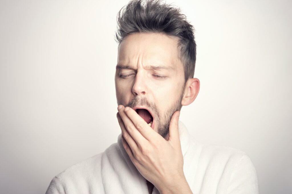  A man yawning with a frown.