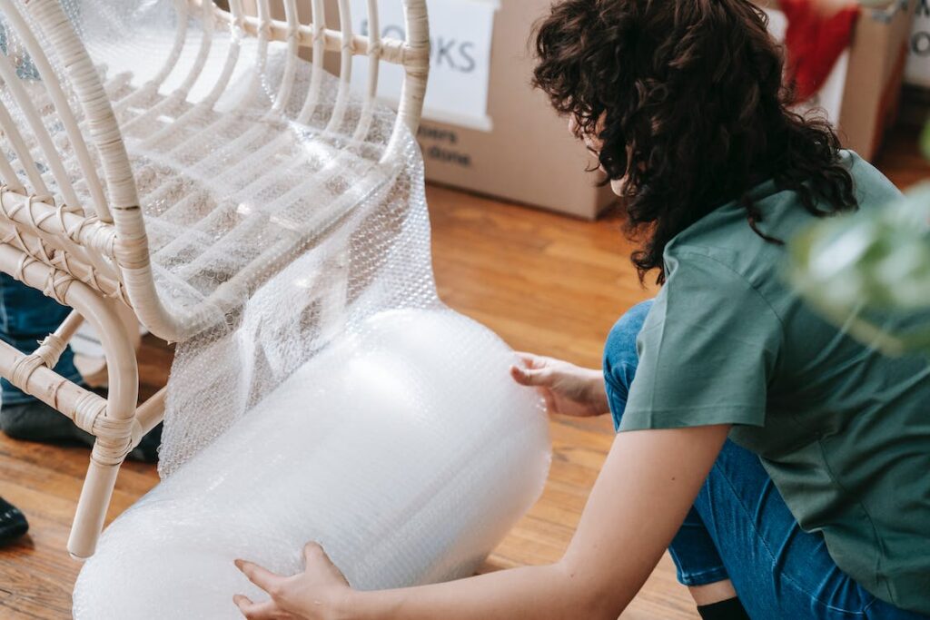 Person using bubble wrap to protect furniture during a move