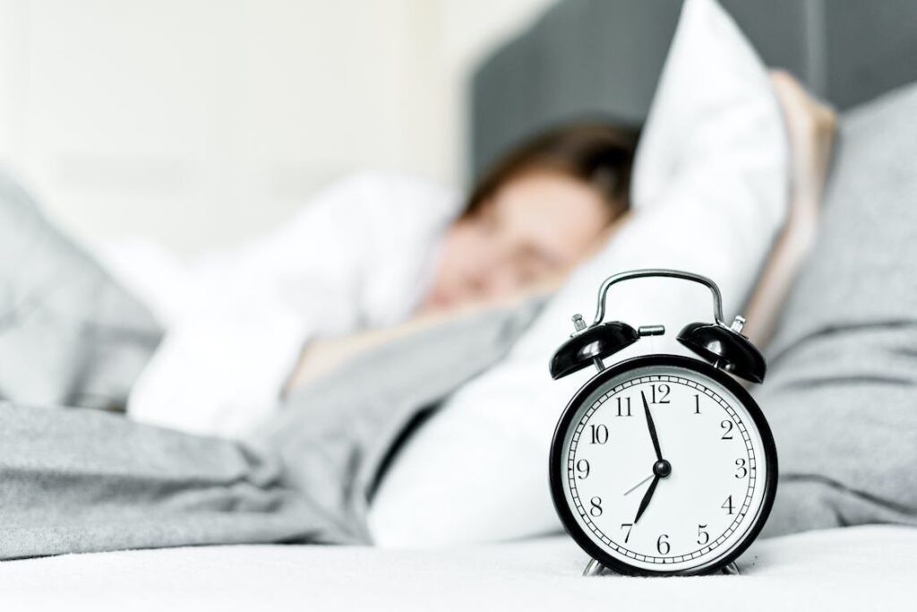 an alarm clock near a sleeping woman