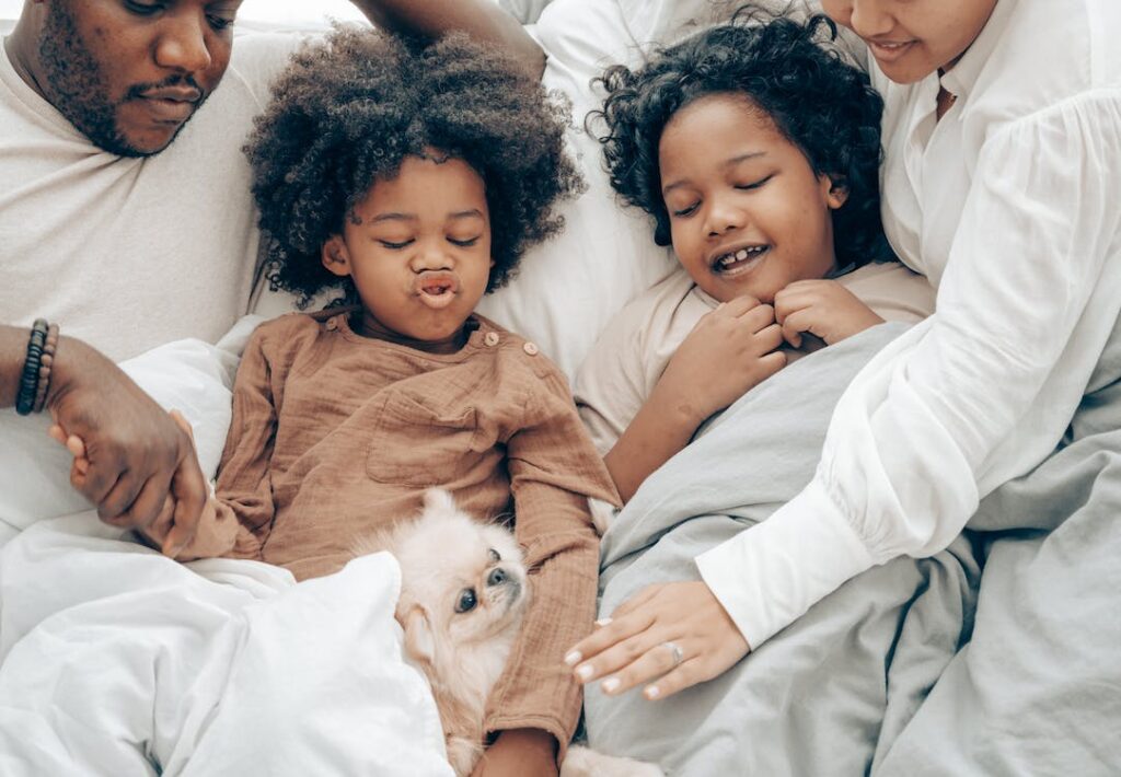  A family in bed with a small dog.