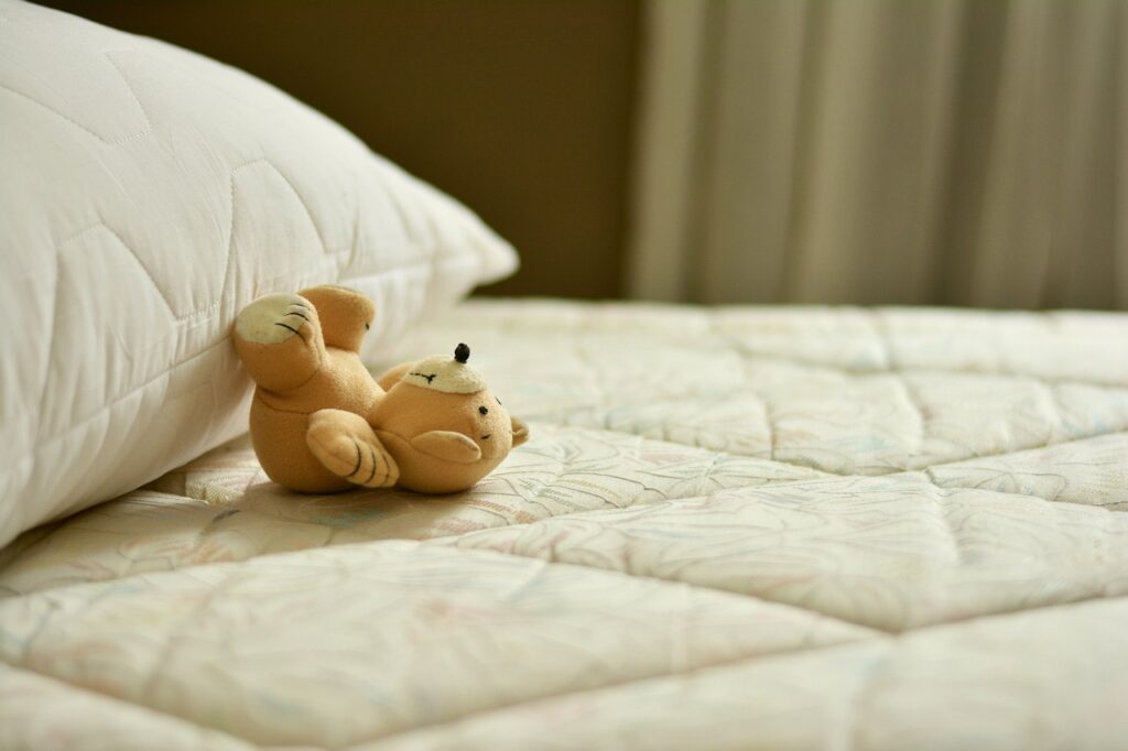 A teddy bear on top of a bed being set up