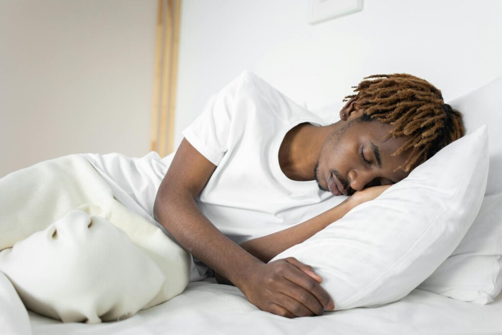 A person in a white shirt napping on a bed